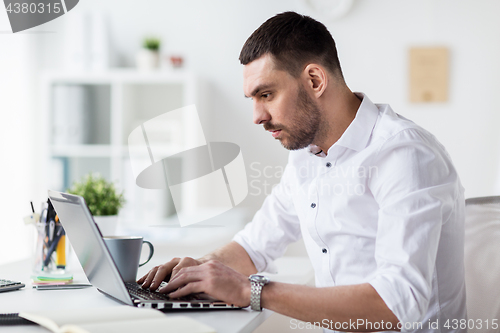 Image of businessman typing on laptop at office