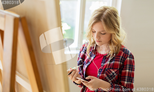 Image of teenage girl with smartphone at art school studio