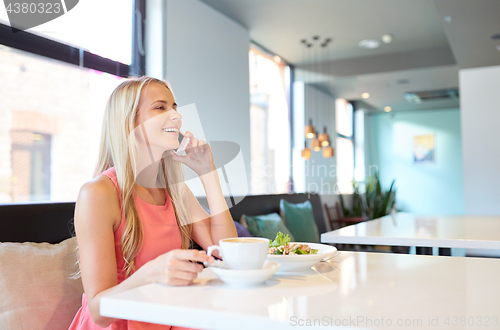 Image of woman with coffee calling smartphone at restaurant