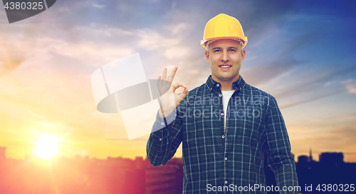 Image of smiling builder in helmet showing ok hand sign