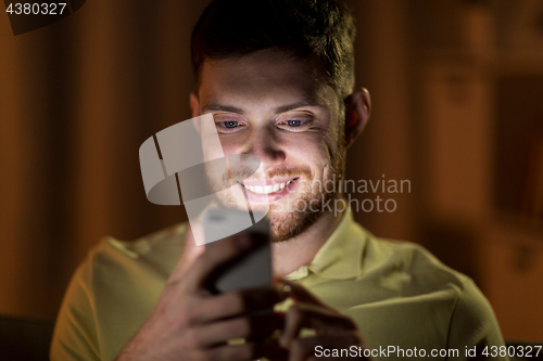 Image of happy young man with smartphone at night