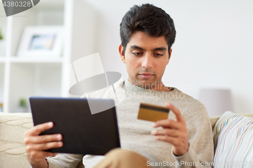 Image of man with tablet pc and credit card at home