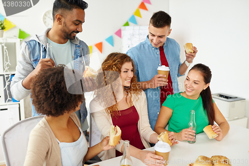 Image of happy friends or team eating at office party