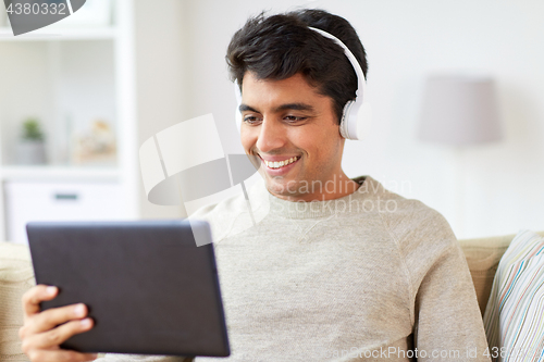 Image of man in phones with tablet pc listening to music