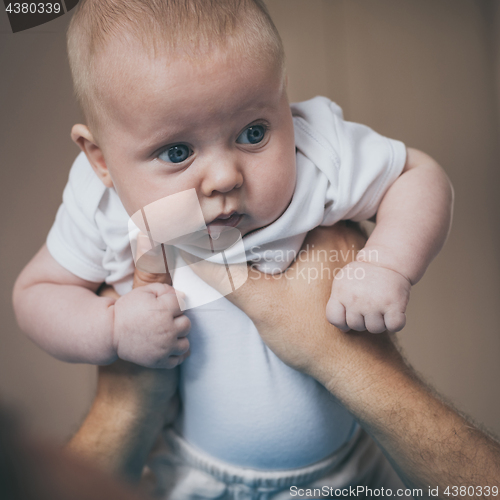 Image of Father and baby son  playing on the bed.