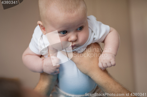 Image of Father and baby son  playing on the bed.