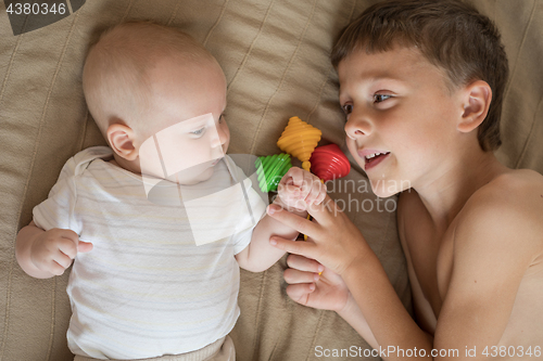 Image of little boy playing with newborn on the bed 