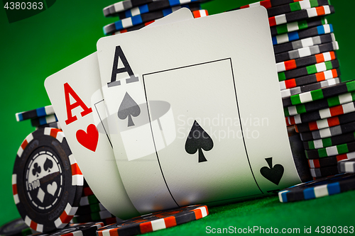 Image of Stack of chips and two aces on the table on the green baize