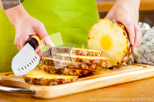 Image of Woman\'s hands cutting pineapple