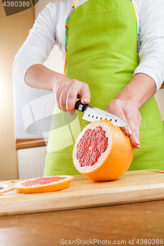 Image of Woman\'s hands cutting grapefruit