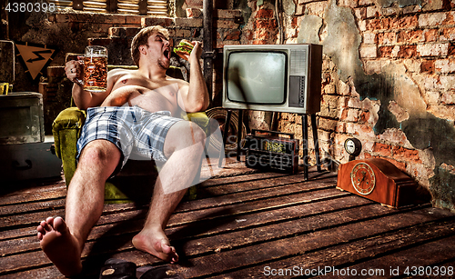 Image of Fat man eating a hamburger sitting on a chair in the slums