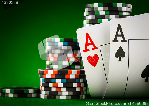 Image of Stack of chips and two aces on the table on the green baize