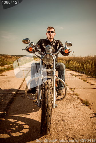 Image of Biker in a leather jacket riding a motorcycle on the road