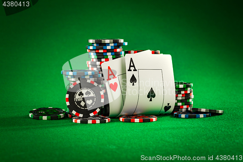 Image of Stack of chips and two aces on the table on the green baize