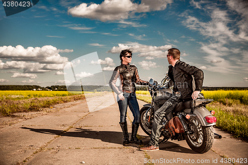 Image of Bikers couple Man and woman near a motorcycle on the road