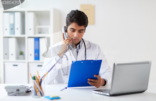 Image of doctor with clipboard calling on phone at clinic