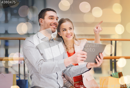 Image of couple with tablet pc and shopping bags in mall