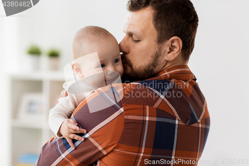 Image of happy father kissing little baby boy at home