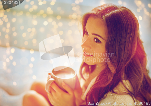 Image of happy woman with cup of cocoa in bed at home