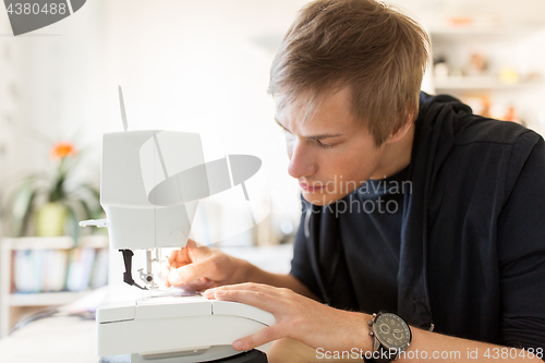 Image of fashion designer with sewing machine at studio