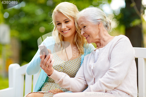 Image of daughter and senior mother with smartphone at park