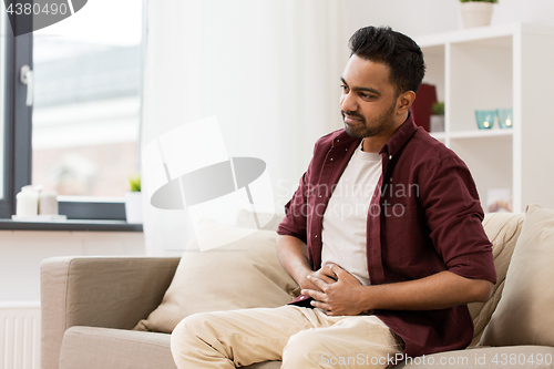 Image of unhappy man suffering from stomach ache at home