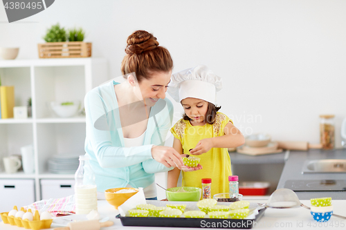 Image of happy mother and daughter baking cupcakes at home