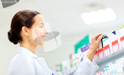 Image of happy female apothecary with drug at pharmacy