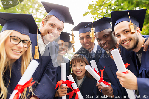 Image of happy students in mortar boards with diplomas