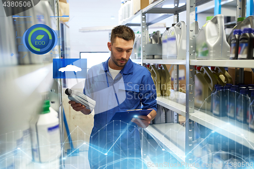 Image of auto mechanic with oil and clipboard at car shop