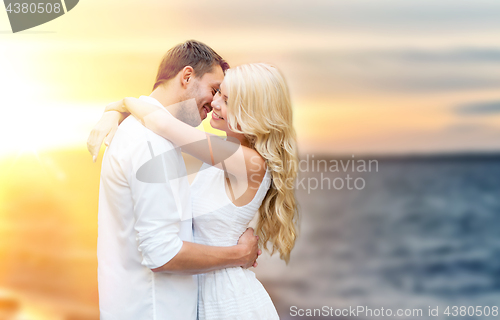 Image of happy couple hugging and kissing on summer beach