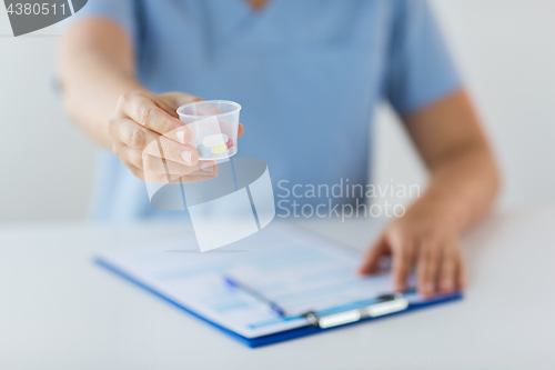 Image of close up of doctor with pills in medical cup