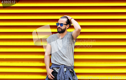 Image of man in sunglasses over ribbed yellow background