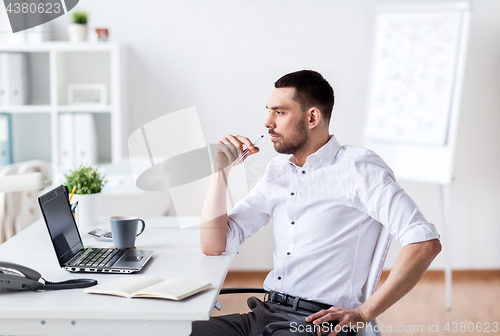 Image of businessman with laptop and notebook at office