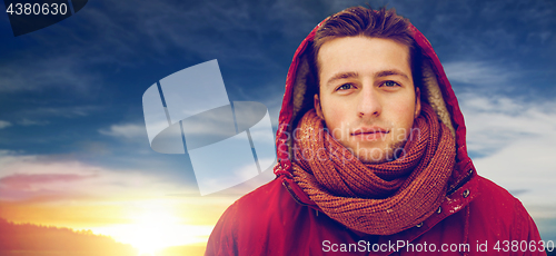 Image of happy man in winter jacket with hood outdoors