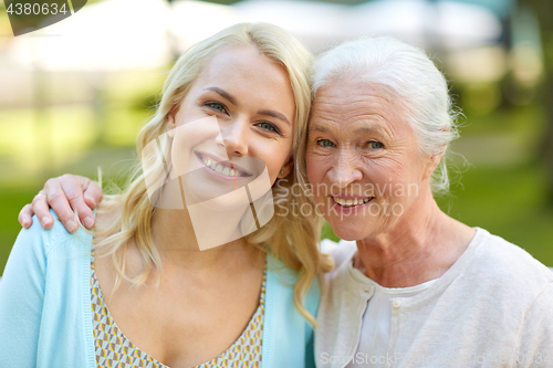 Image of daughter with senior mother hugging on park bench