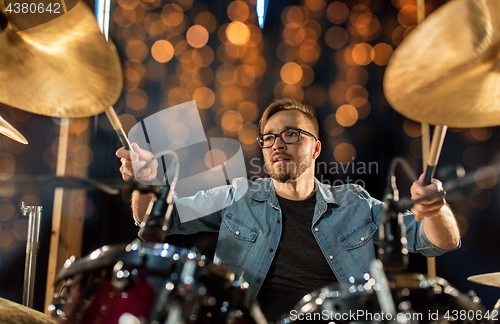 Image of musician playing drum kit at concert over lights