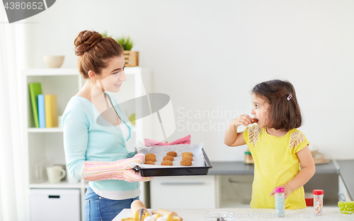 Image of happy mother and daughter baking cookies at home