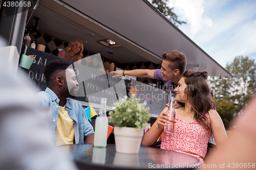 Image of friends with drinks sitting at table at food truck