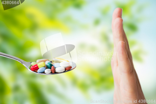 Image of hand of woman refusing from pills on spoon