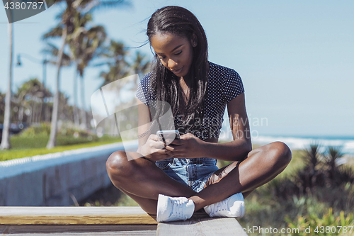 Image of Beautiful woman using phone on fence