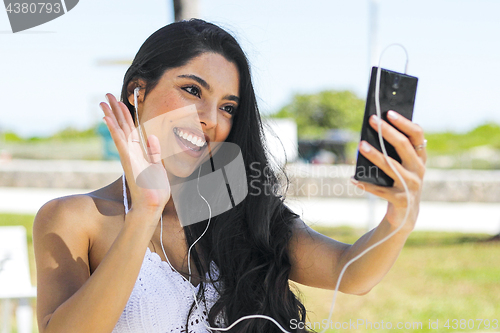 Image of Laughing girl chatting online with phone in park