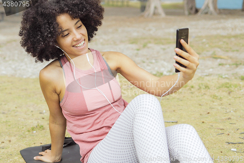 Image of Charming girl having videocall on mat in park