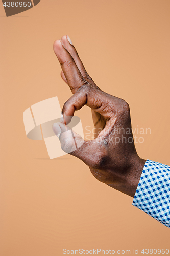 Image of Hand showing OK sign isolated on brown background.