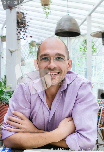 Image of Cheerful Bald Man Sitting On A Summer Terrace