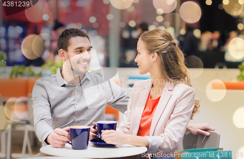 Image of happy couple with shopping bags drinking coffee