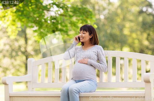 Image of pregnant asian woman calling on smartphone at park