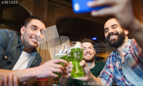 Image of friends taking selfie with green beer at pub