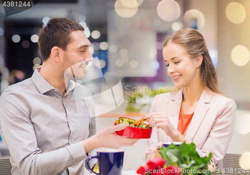 Image of happy couple with present and flowers in mall