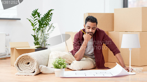 Image of man with blueprint and boxes moving to new home